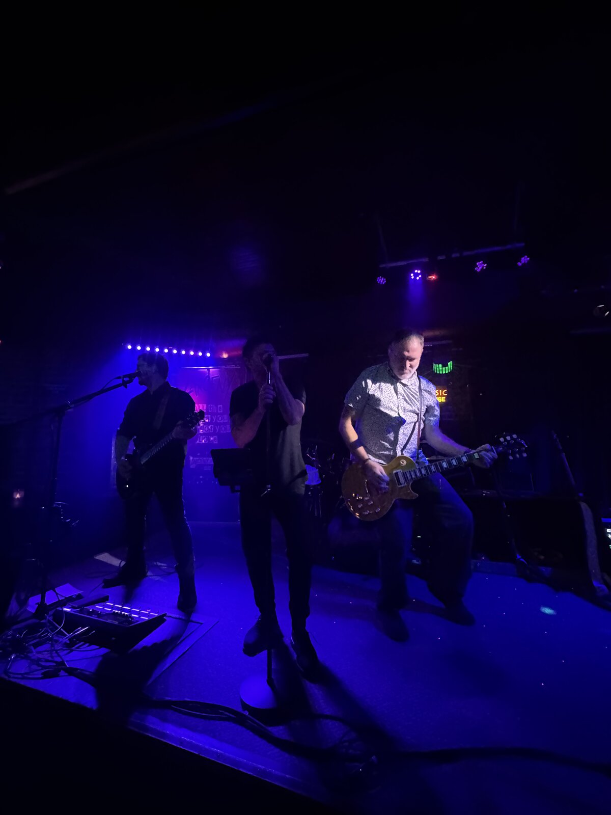 Larceny vocalist Erik and lead guitarist Kevin performing under blue lights at Sky Music Lounge