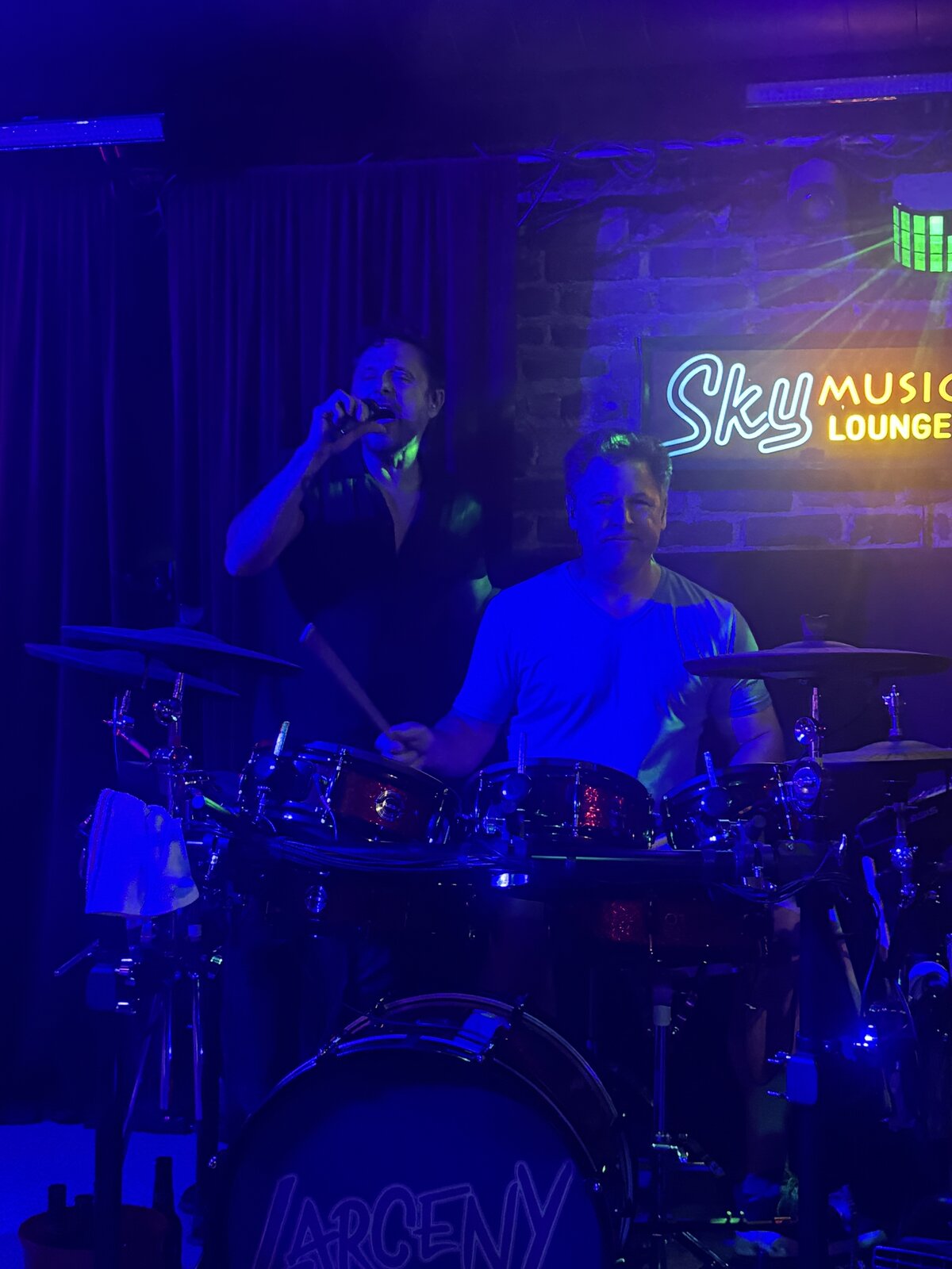 Larceny vocalist Erik singing with drummer John behind the Larceny drum kit at Sky Music Lounge