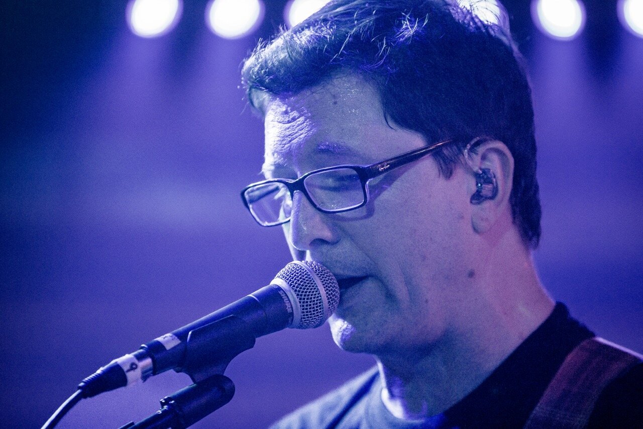 Dan Lastovka close-up singing into microphone with in-ear monitors at Sky Music Lounge