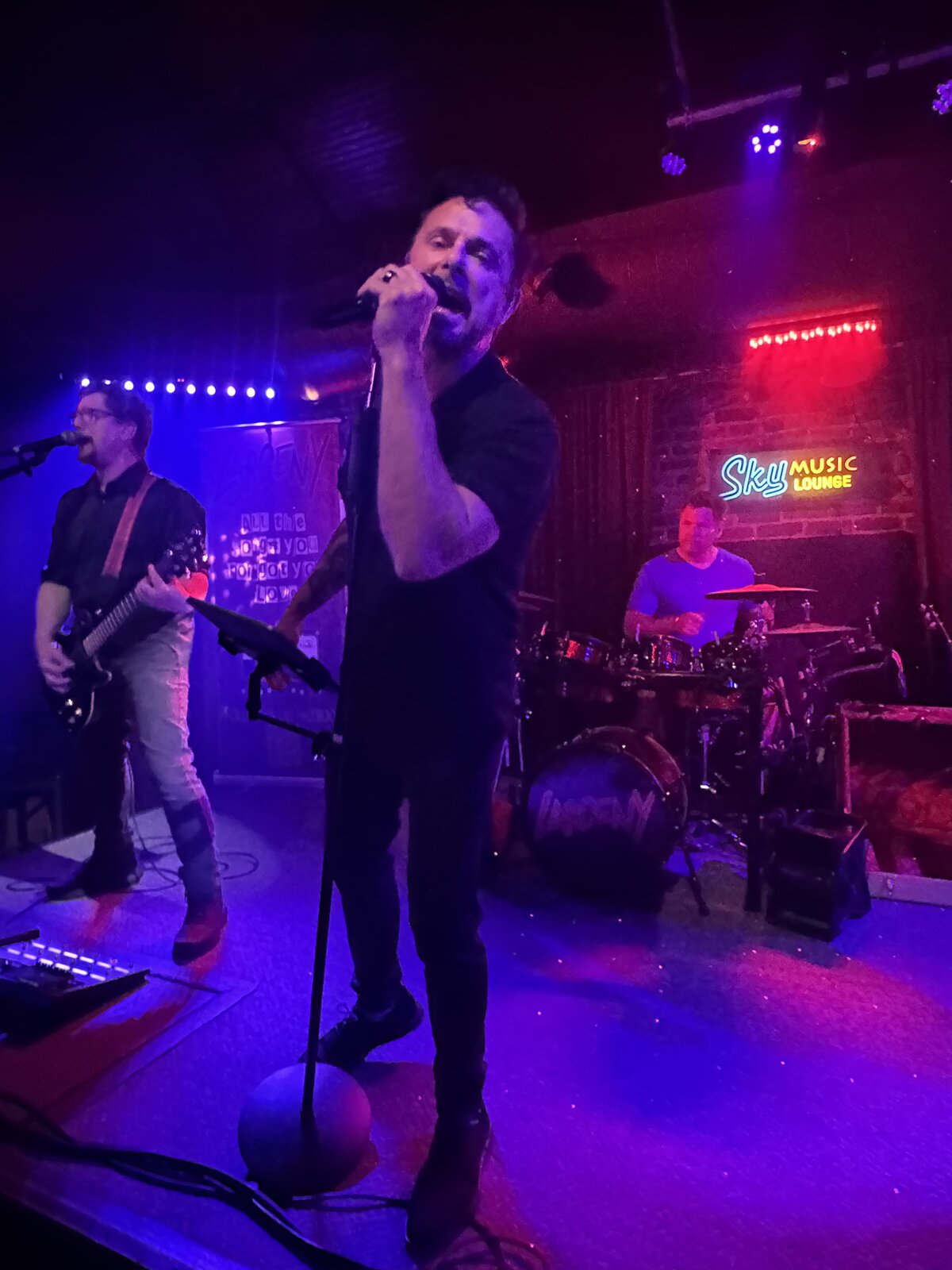 Erik Wilson singing on stage with Sky Music Lounge neon sign behind him