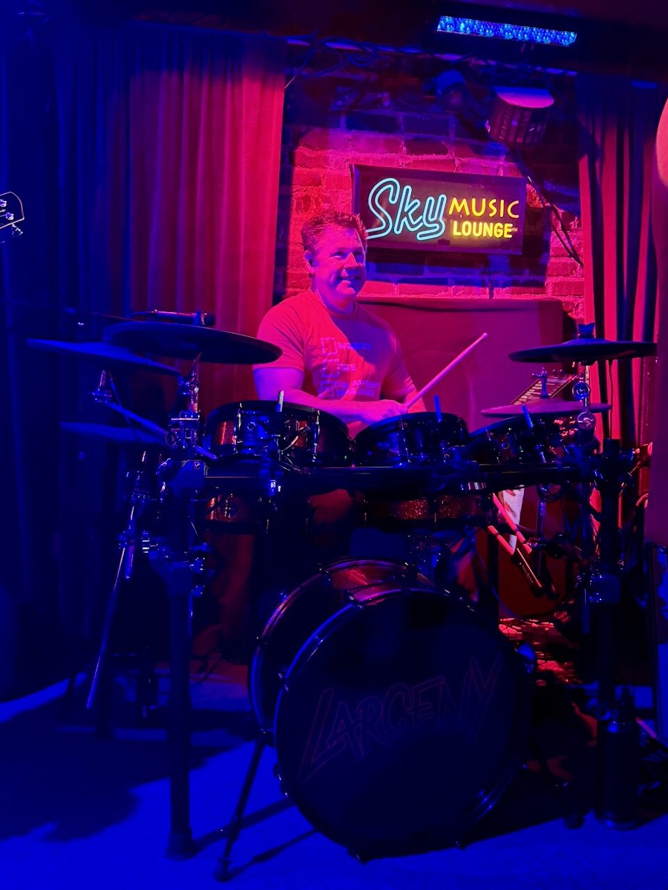 John Ebersohl smiling behind the Larceny drum kit at Sky Music Lounge