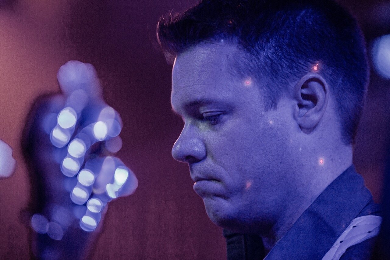 Tim Rooney close-up profile with stage lights at Sky Music Lounge